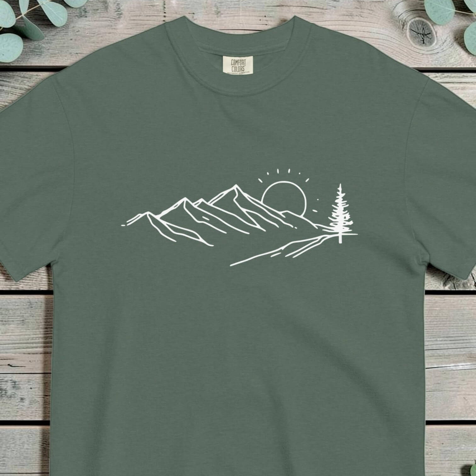 Mountain sunrise line design on a Blue Spruce garment-dyed cotton t-shirt