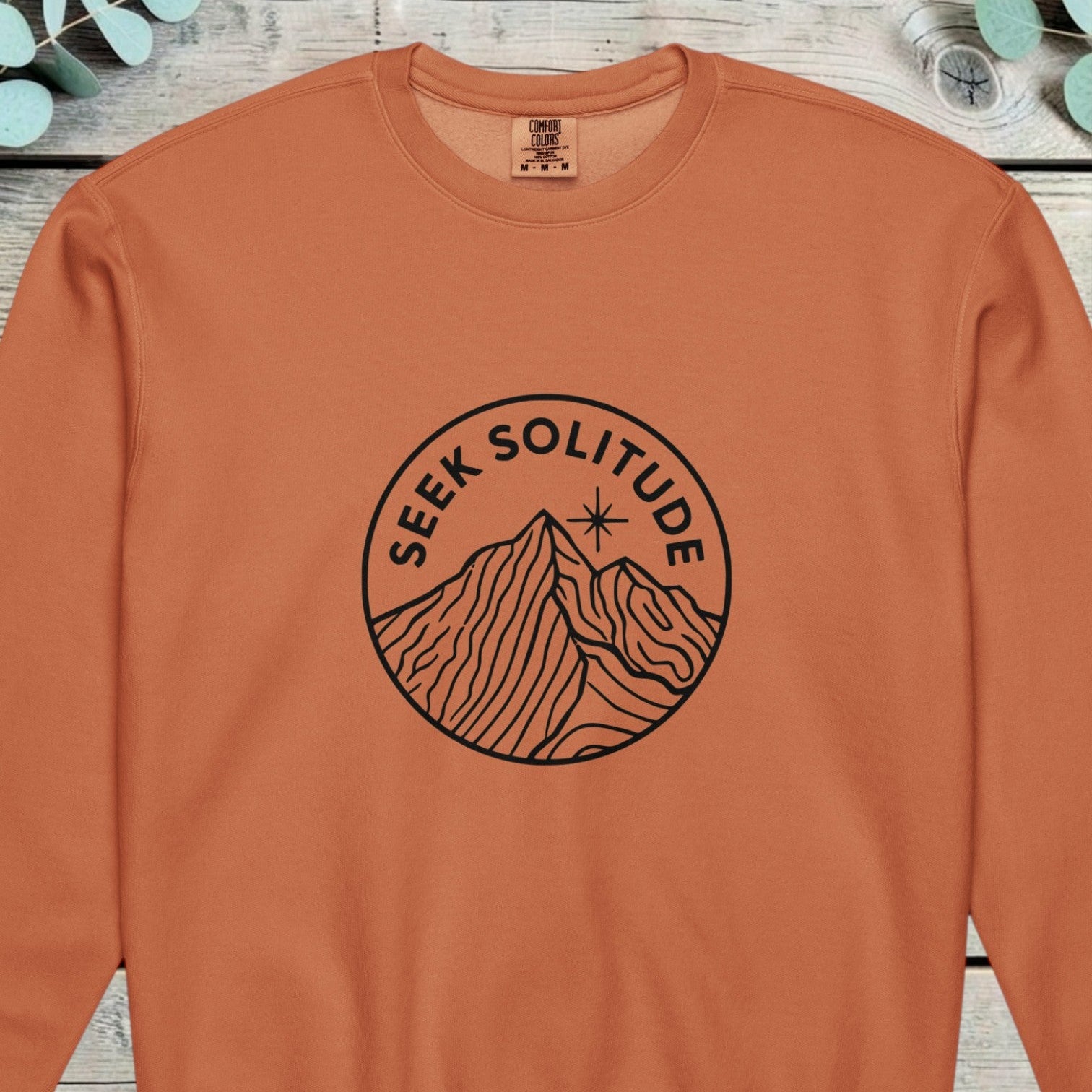 Circular line badge showing a mountain peak and a small star, reading SEEK SOLITUDE