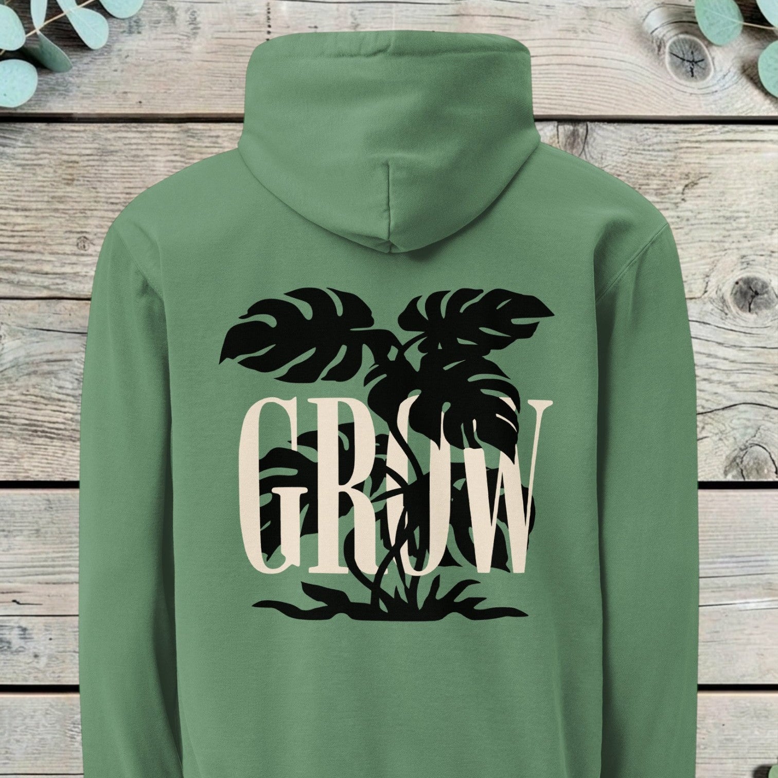Large back print of a monstera plant silhouette behind the word GROW in serif capitals