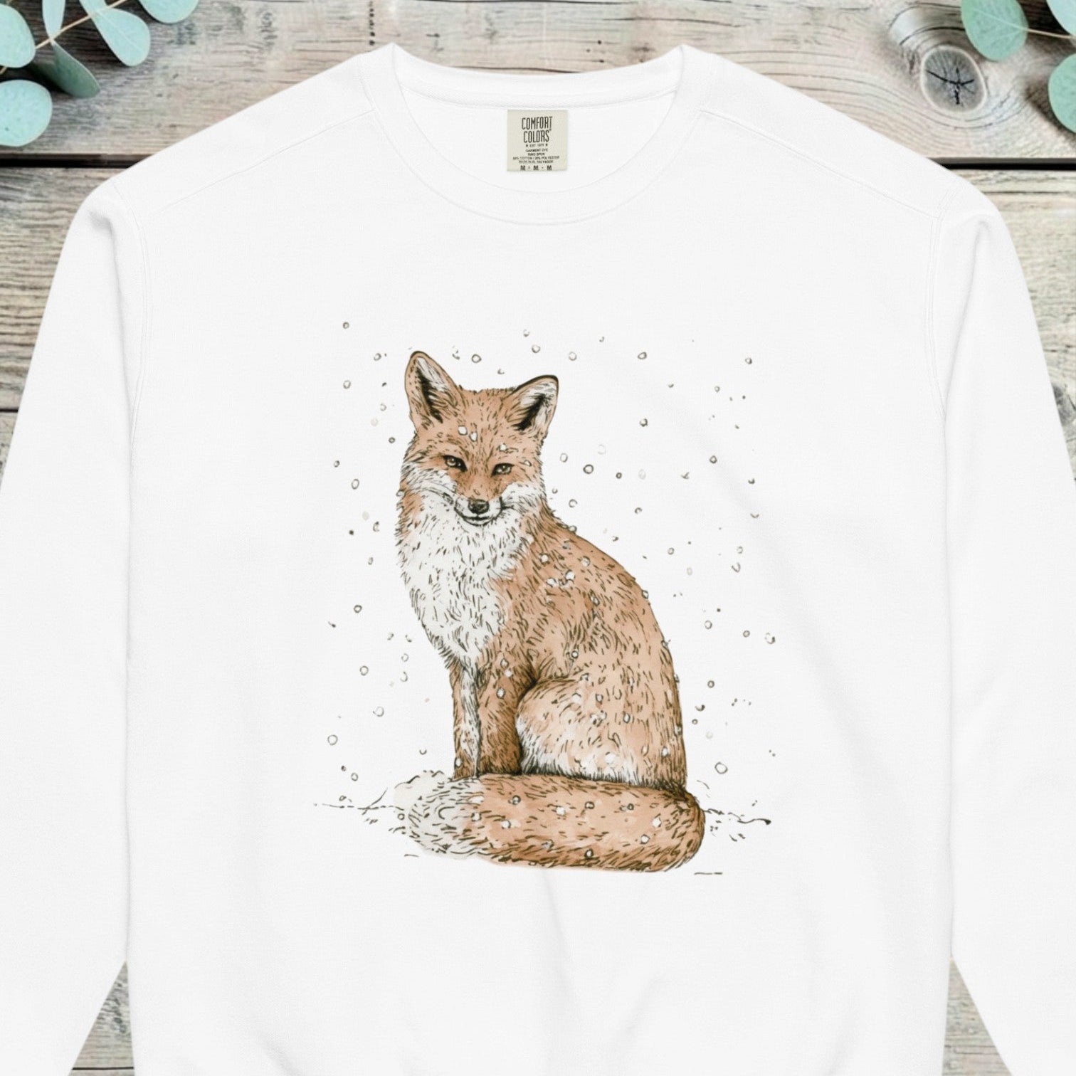 Red fox sitting calmly with light snow falling around it