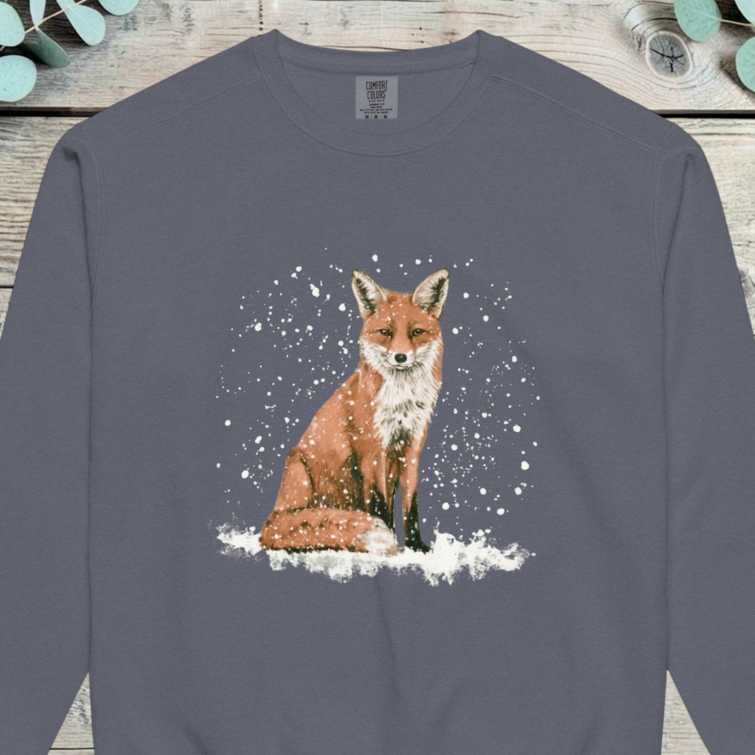 Red fox sitting on snow-covered ground with heavy snow falling around it