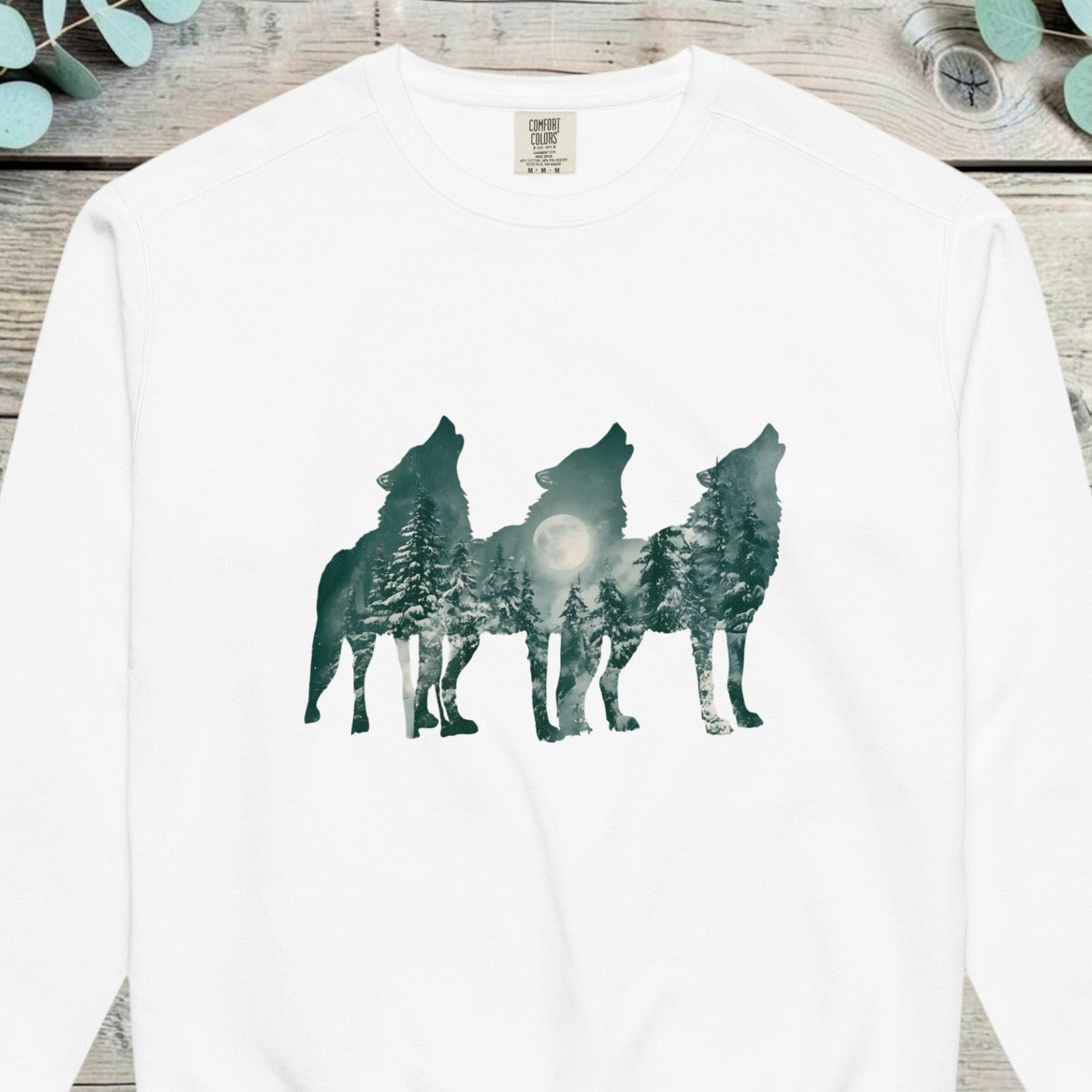 Three howling wolf silhouettes filled with a moonlit pine forest