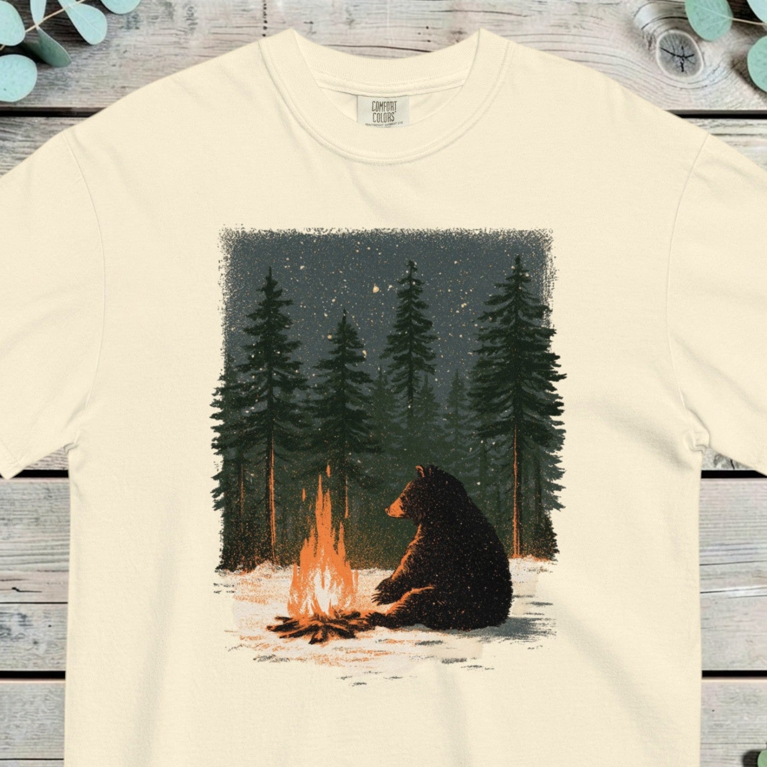 Black bear sitting beside a campfire in snowy pine woods under a starry sky