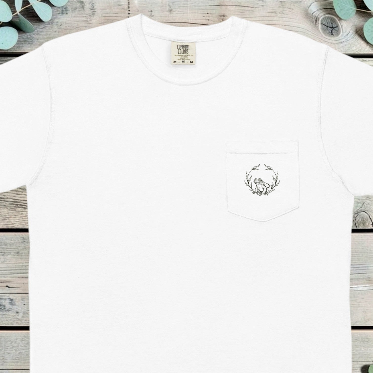 Small holly wreath with a frog printed on the chest pocket of a t-shirt