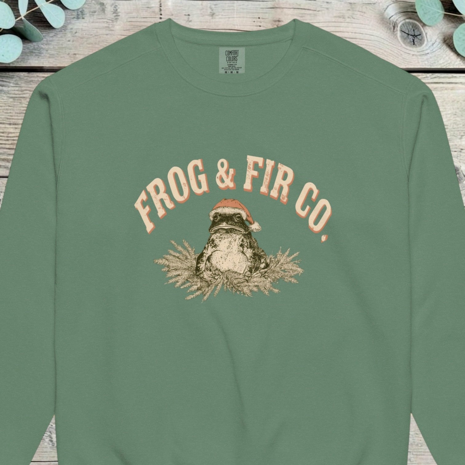 Toad wearing a mushroom cap hat sitting among ferns beneath arched lettering