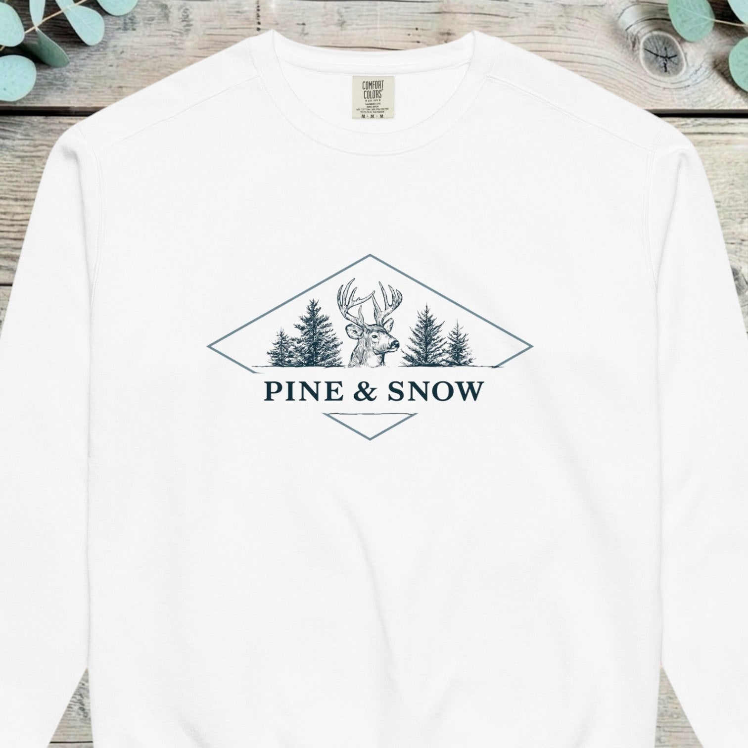 Stag head flanked by pine trees inside a diamond with PINE AND SNOW beneath it