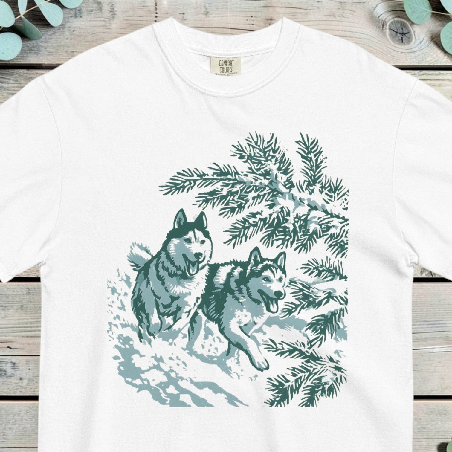 Two huskies running at full stretch through deep snow past winter pines