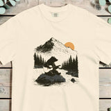 Bear sitting on a rock playing an acoustic guitar with pines and a mountain behind