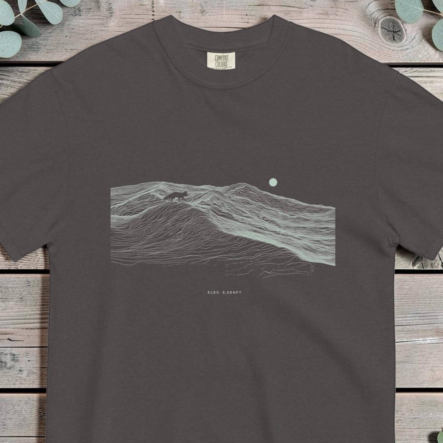 Small fox silhouette walking a ridgeline built from topographic contour lines under a moon
