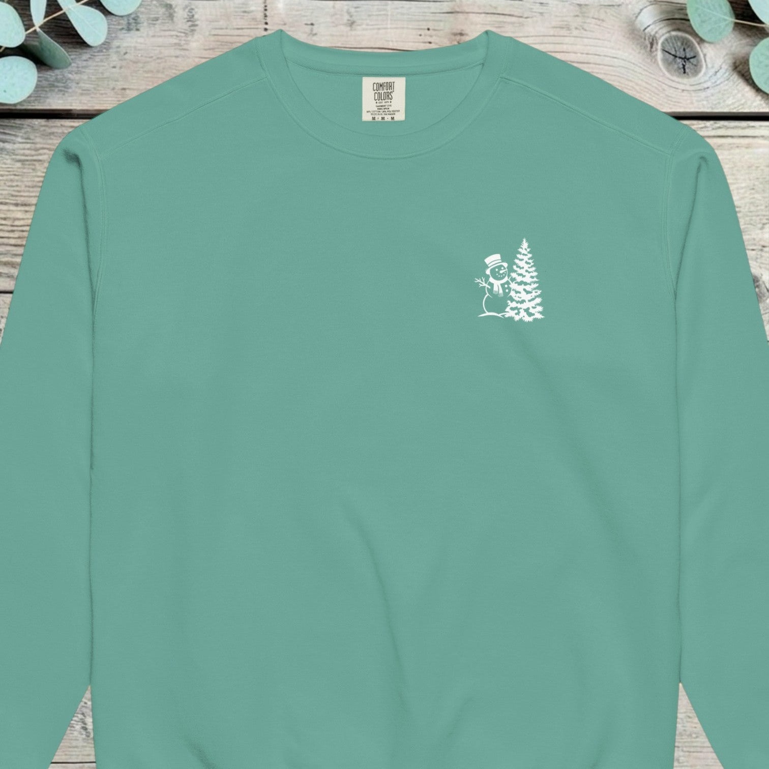 Small chest design of a top-hatted snowman beside a Christmas tree on a sweatshirt