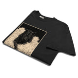 Black wolf in deep snow design on a Black garment-dyed cotton t-shirt